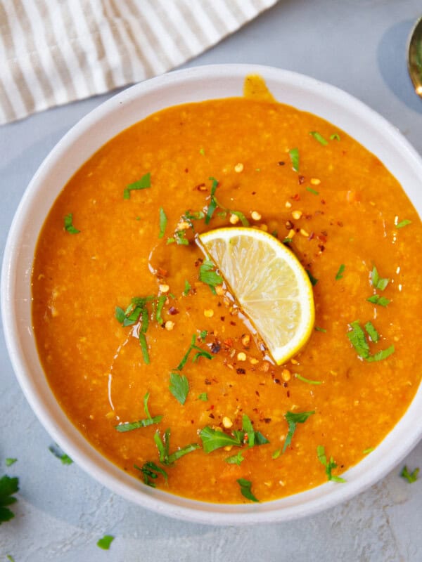 Warm bowl of Instant Pot red lentil soup topped with lemon, parsley, and chili flakes.