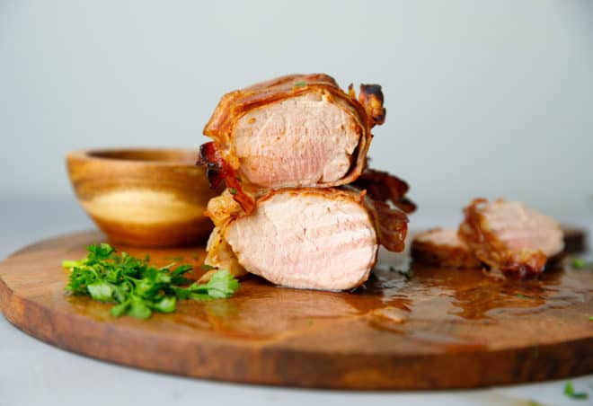 Carne de cerdo envuelta en lomo en una tabla de cortar cortada por la mitad