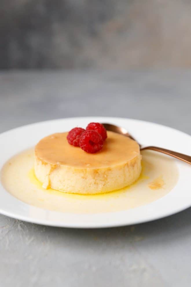 Keto flan on a white plate topped with berries