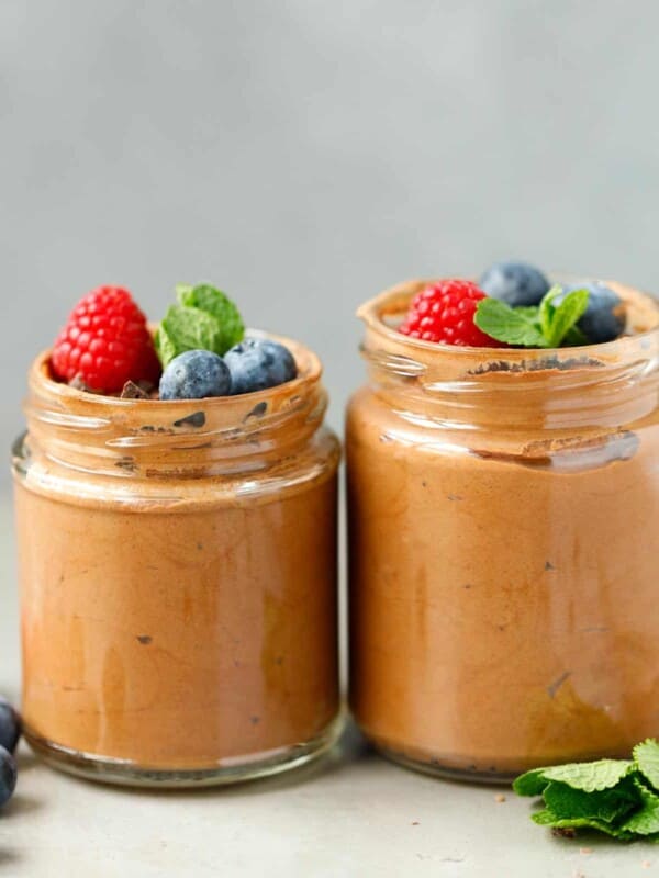 Two jars with vegan chocolate mousse topped with berries
