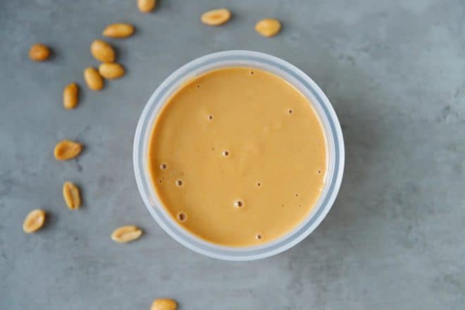 A round plastic container with creamy homemade peanut butter