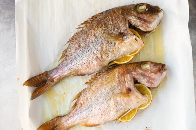 Two roasted Fagri fishes on parchment paper