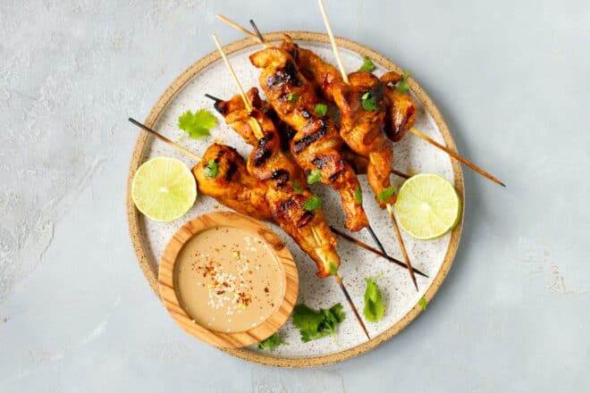 Chicken Satay skewers on a plate with peanut sauce