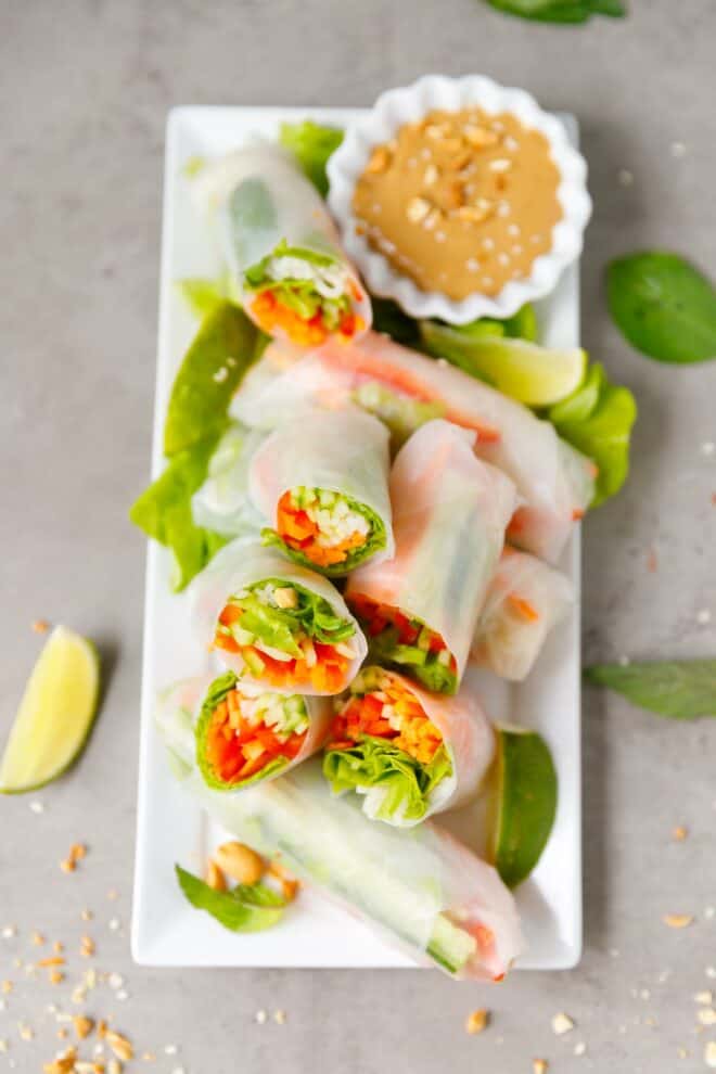 A white platter with fresh Vietnamese spring rolls and small bowl of peanut sauce