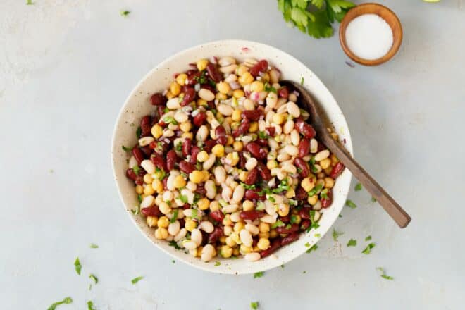 Three bean salad in a bowl with wooden spoon