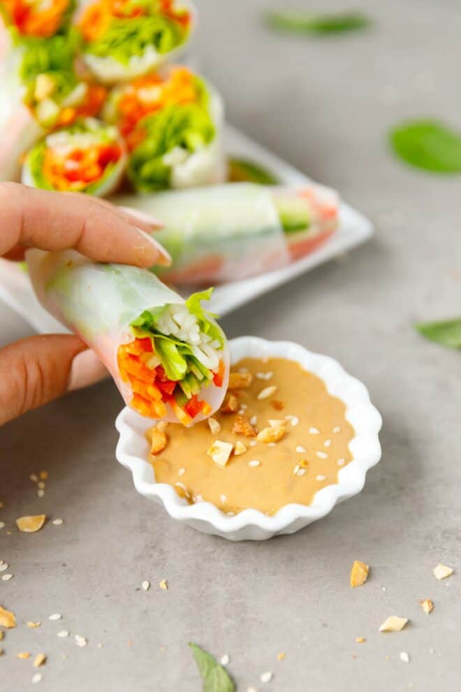A hand holding Fresh spring rolls with peanut sauce 