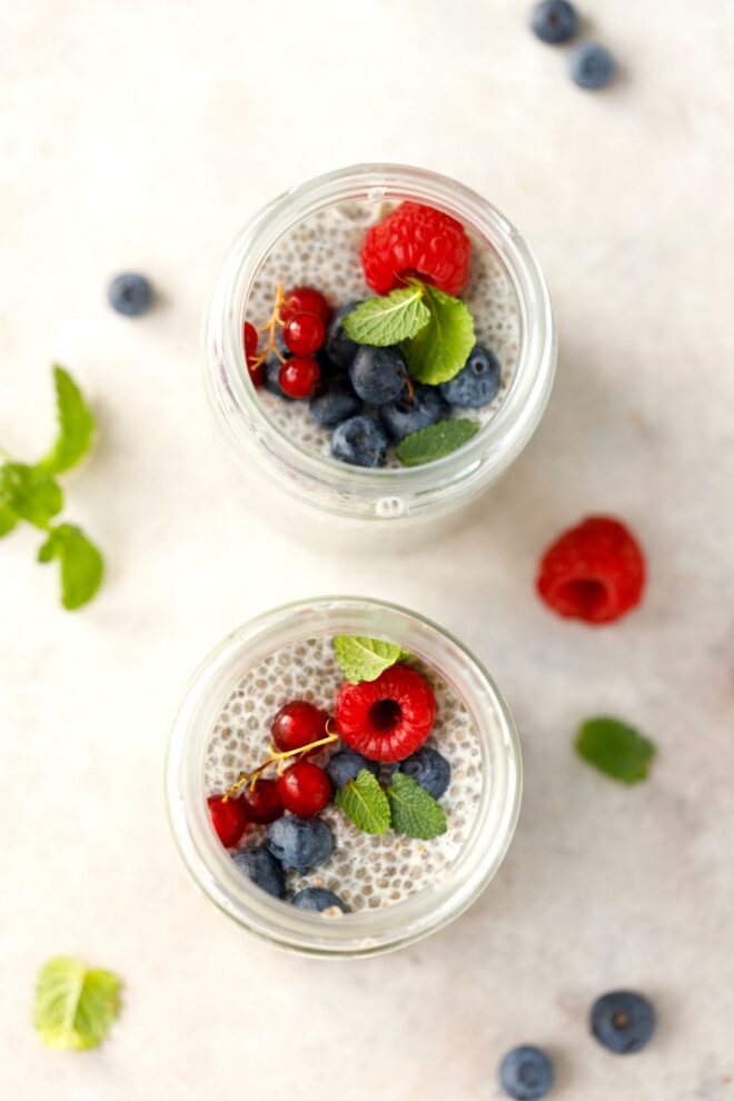Two glass jars with chia pudding topped with berries