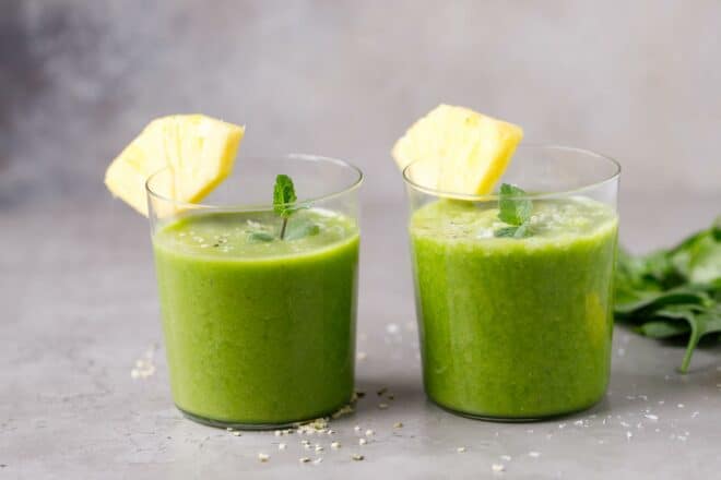 Two cups of pineapple spinach smoothie on a table