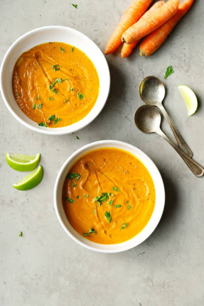 Two bowls with carrot soup on a table