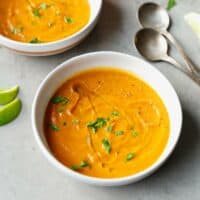 Bowl with carrot soup and lime wedges