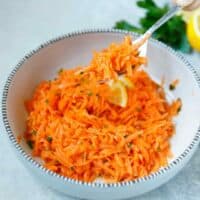 A bowl with shredded carrot salad and a fork