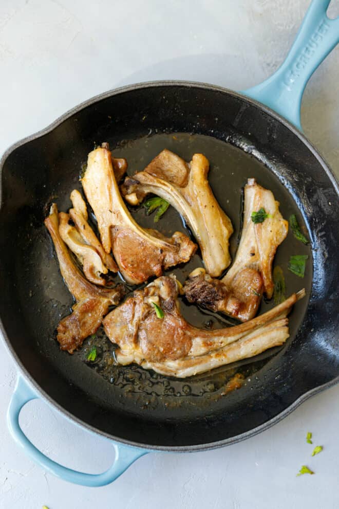 Lamb cutlets in a cast iron pan on a gray table