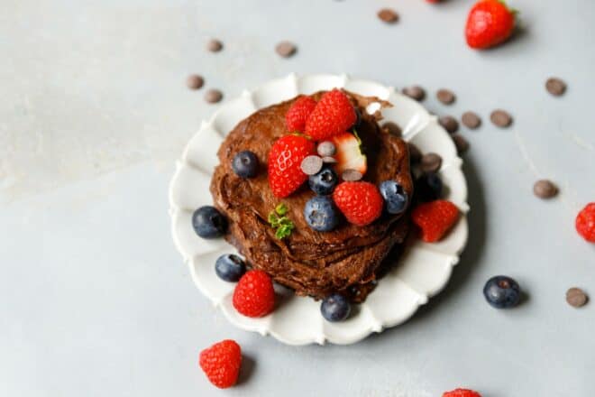 Keto chocolate pancakes on a plate, topped with berries