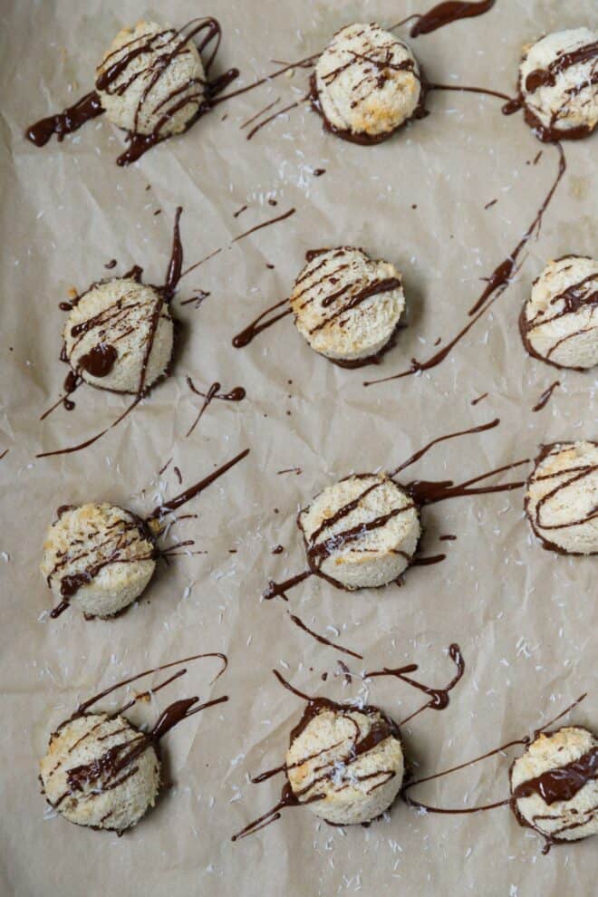 Coconut macaroon cookies on a baking sheet, drizzled with melted chocolate