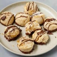 Gluten Free Coconut Macaroons drizzled with chocolate on a speckled plate
