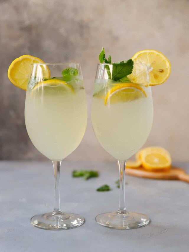 Two wine glasses filled with limoncello spritz cocktail
