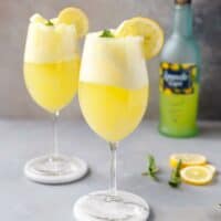 Two wine glasses with limoncello Prosecco ice cream floats and Limoncello bottle next to them