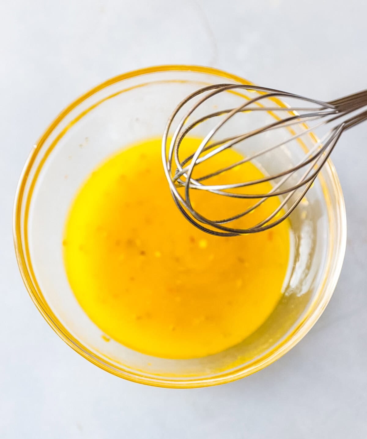 A clear round bowl with Greek salad dressing