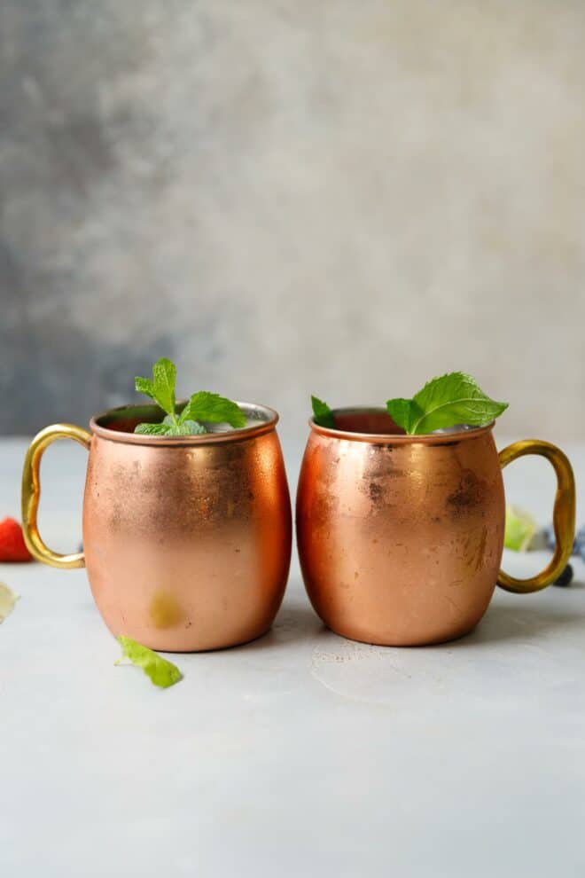 Two copper mugs with berry Moscow Mule