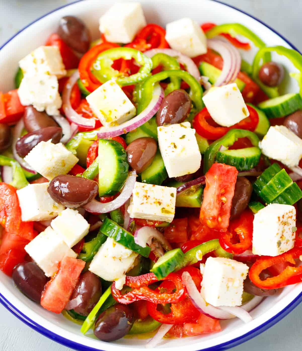 A white bowl with Greek Salad topped with Feta cubes