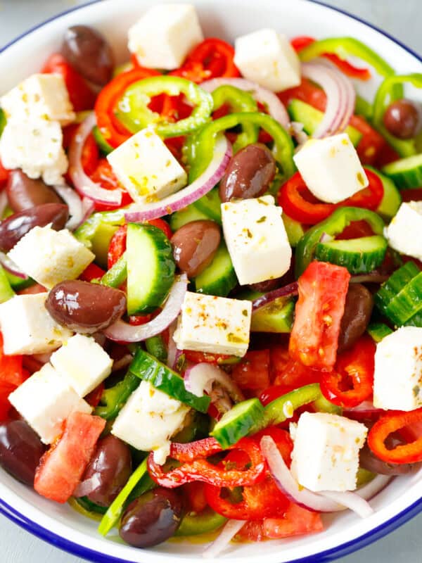 A white bowl with Greek Salad topped with Feta cubes