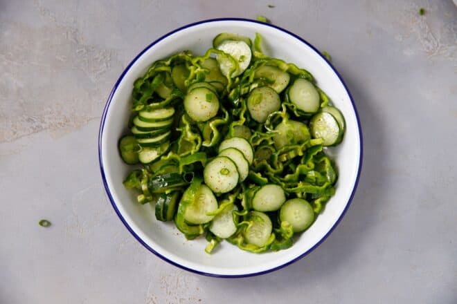 A white bowl with cucumbers and peppers salad