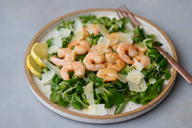 A speckled plate with lamb's lettuce with shrimp and Parmesan cheese