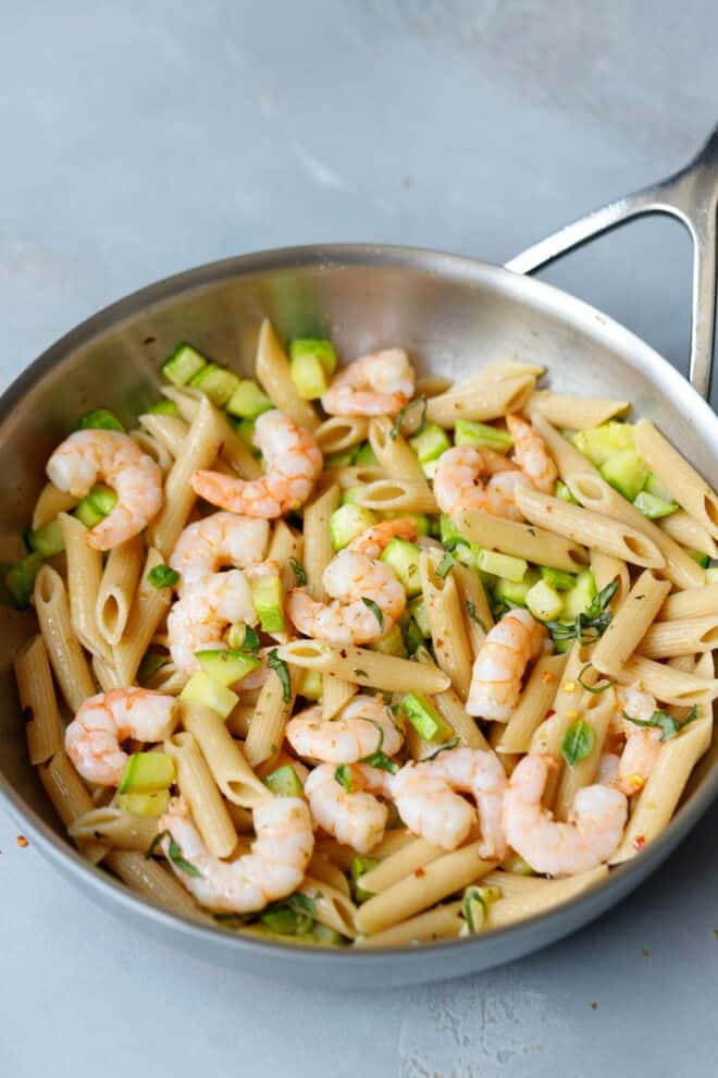 A stainless steel pan with zucchini and shrimp brown pasta