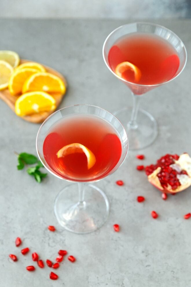Two martini glasses with pomegranate martini inside. 