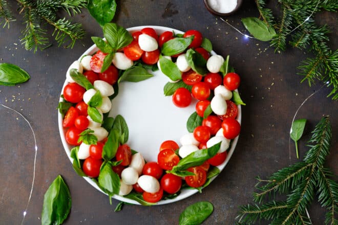 A white ceramic platter with cherry tomato and bocconcini Caprese wreath