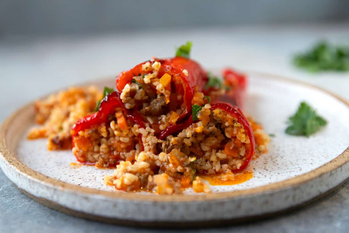 A speckled plate with bulgur stuffed red peppers