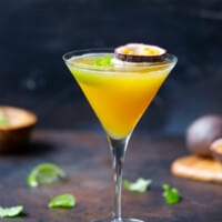 A martini glass with passion fruit cocktail and 1/2 passion fruit on top