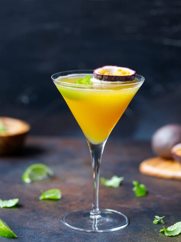 A martini glass with passion fruit cocktail and 1/2 passion fruit on top