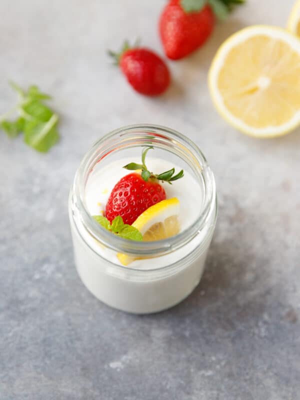 A jar with lemon cottage cheese mousse, garnished with strawberry and lemon slice
