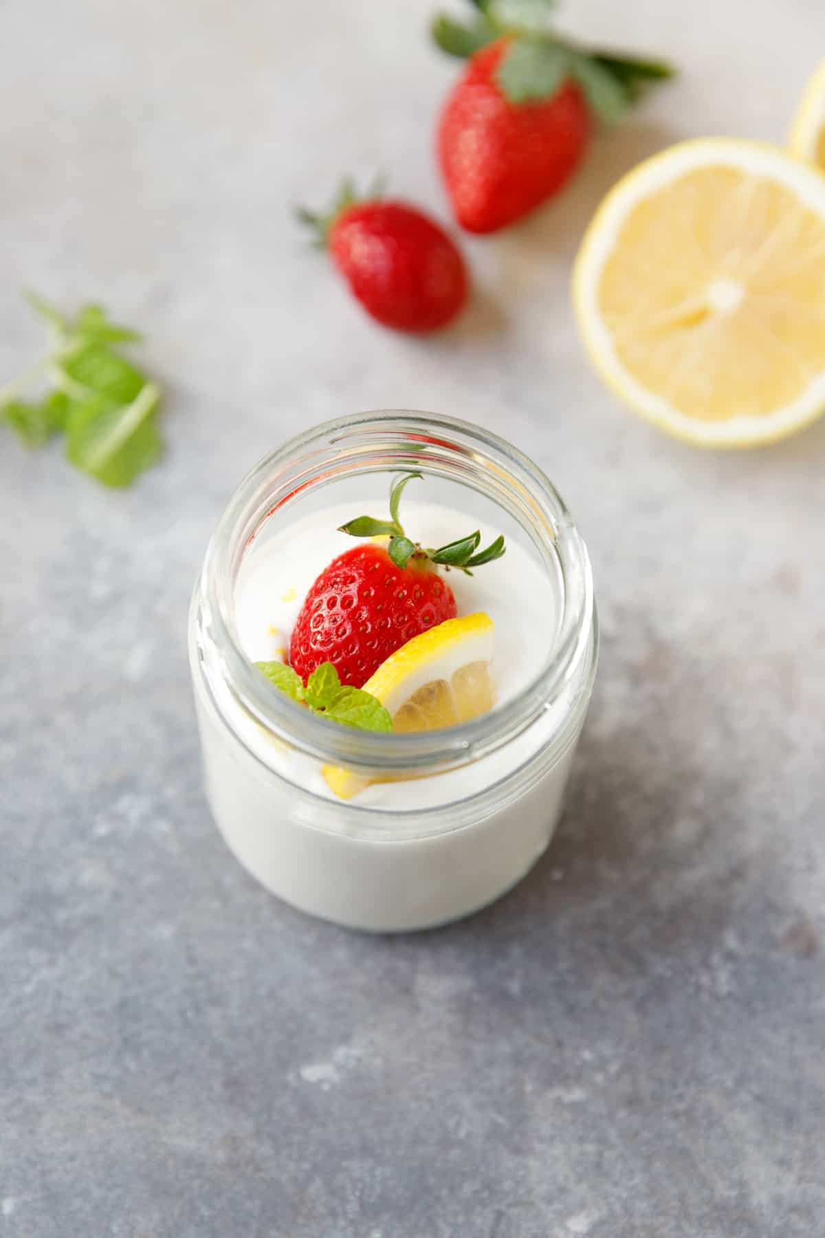 A jar with lemon cottage cheese mousse, garnished with strawberry and lemon slice