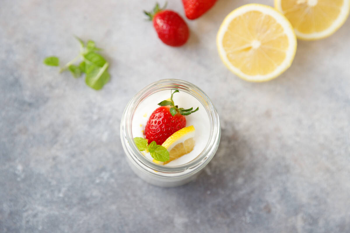 A jar with lemon cottage cheese mousse and sliced lemon next to it.