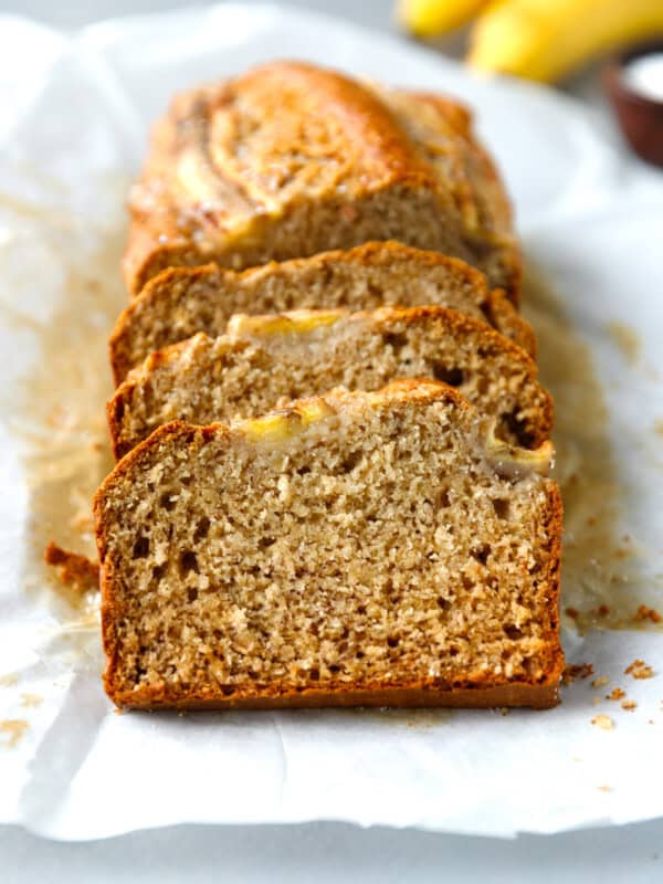 Coconut banana bread sliced on white parchment paper.