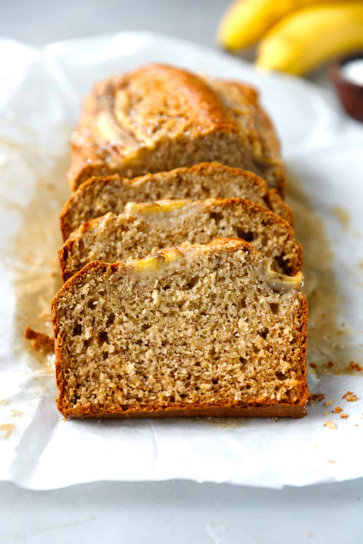Coconut banana bread sliced on white parchment paper.