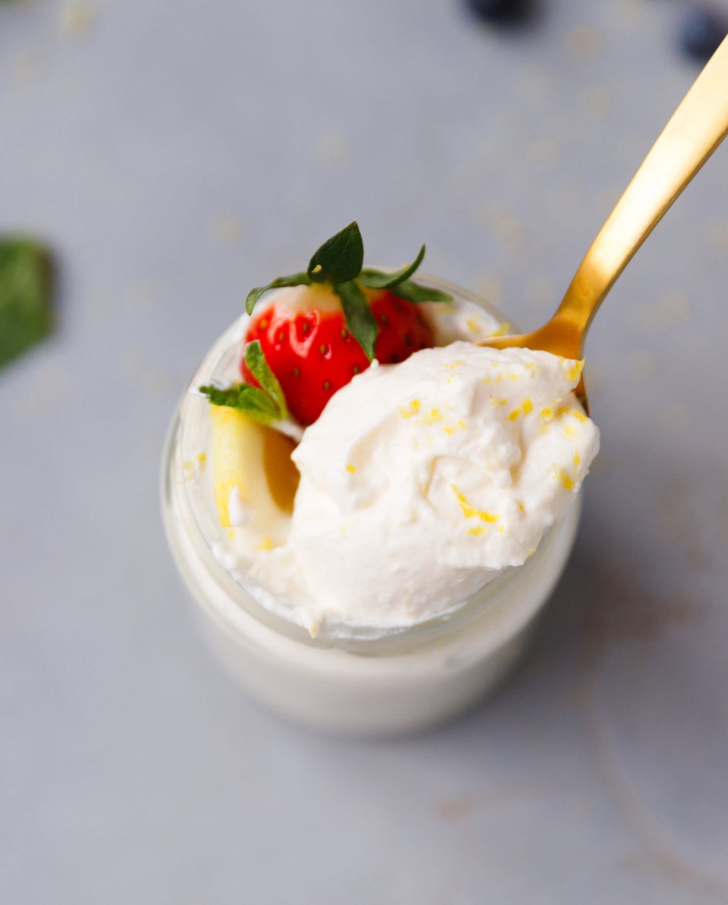 Spoonful of creamy low-carb lemon cottage cheese mousse with strawberry and lemon garnish in a glass jar