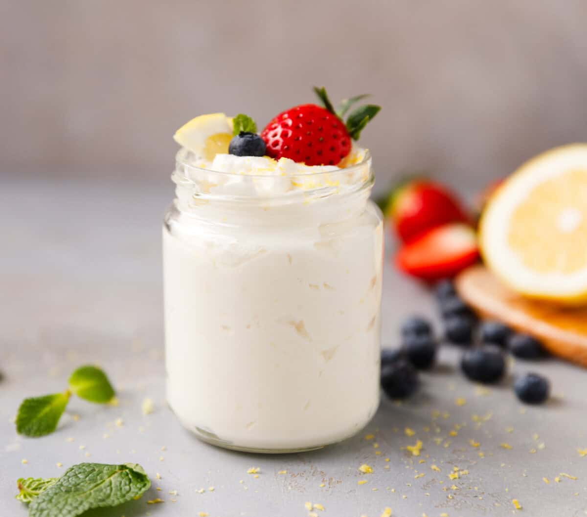 Low-carb lemon cottage cheese mousse in a glass jar topped with strawberry, blueberry, lemon pieces, and fresh mint