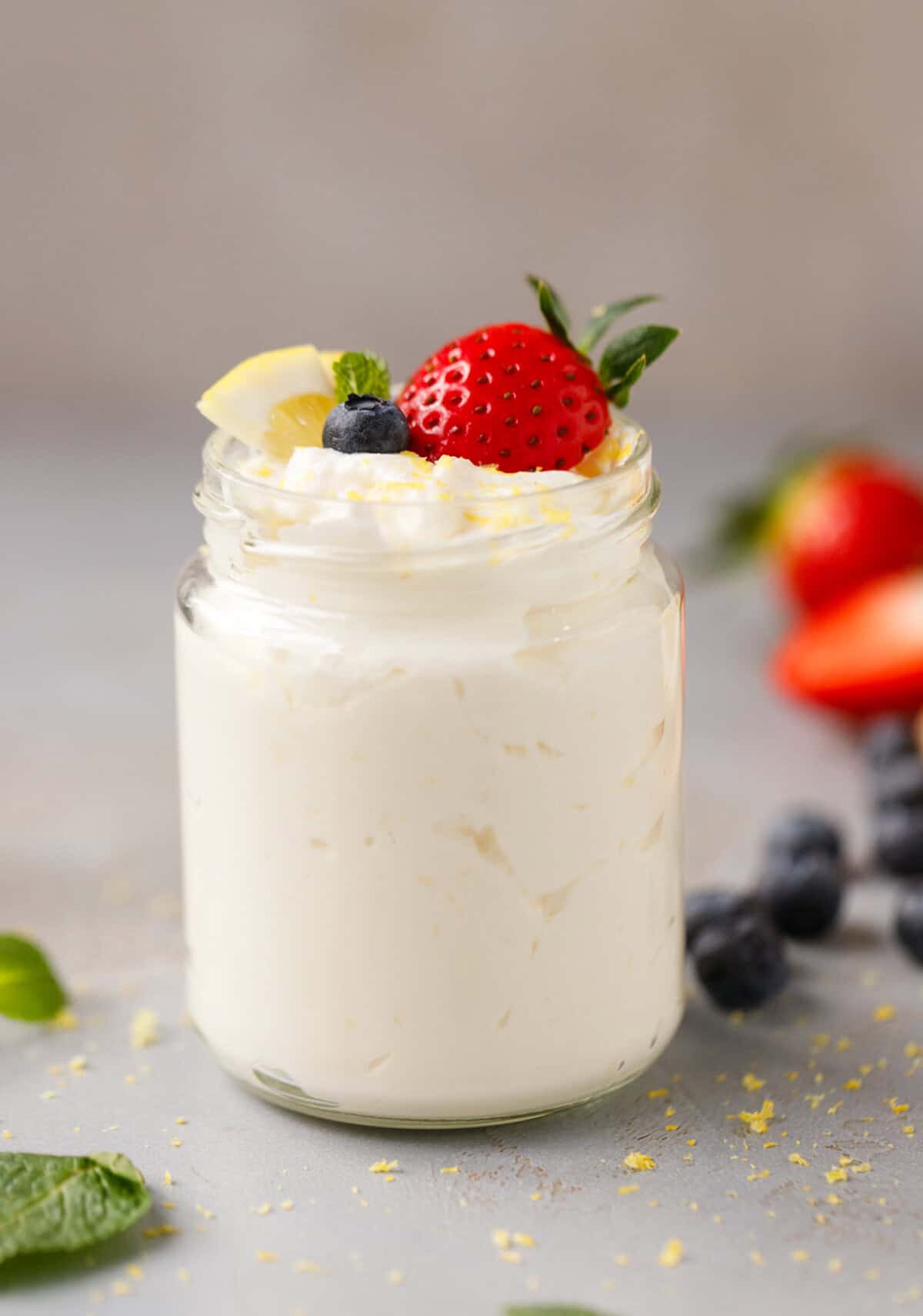 Low-carb lemon cottage cheese mousse in a glass jar with fresh strawberry, blueberry, lemon, and mint on top