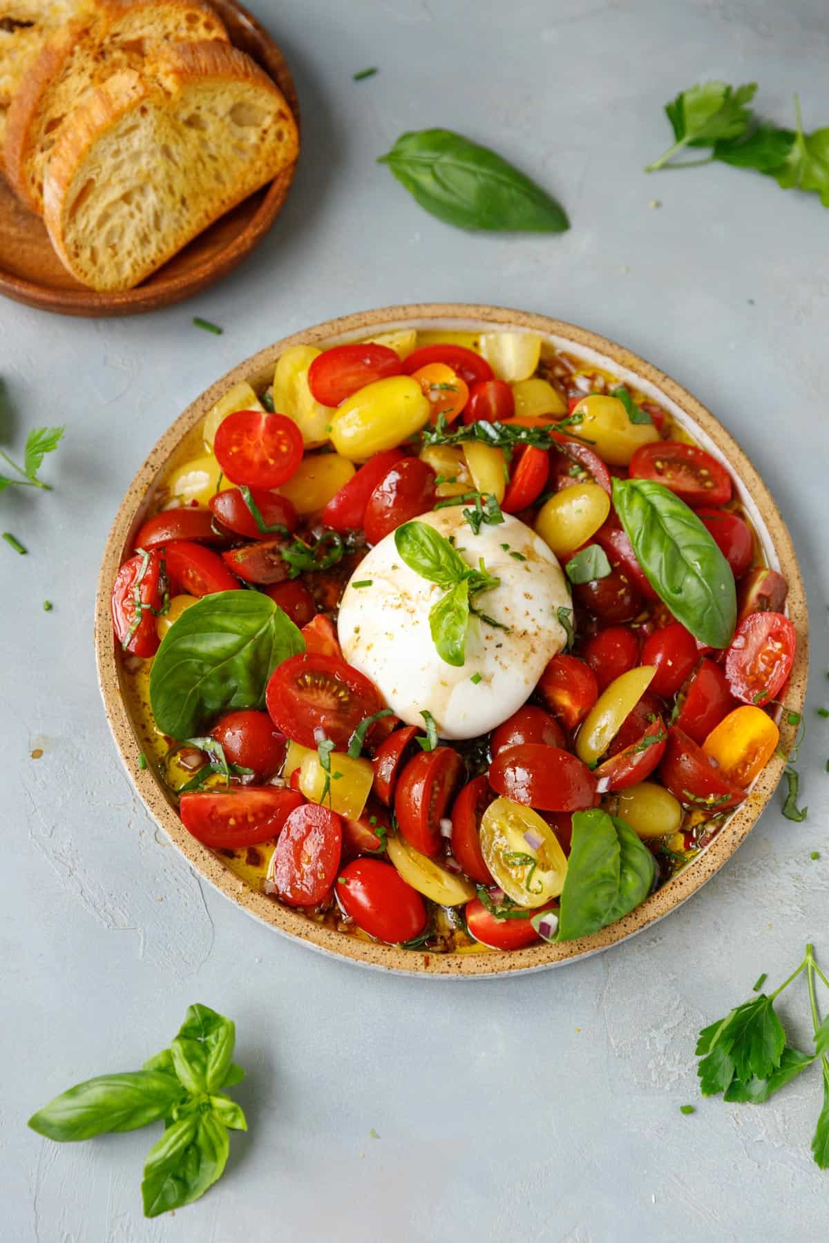 A plate with marinated tomatoes and burrata cheese, topped with basil