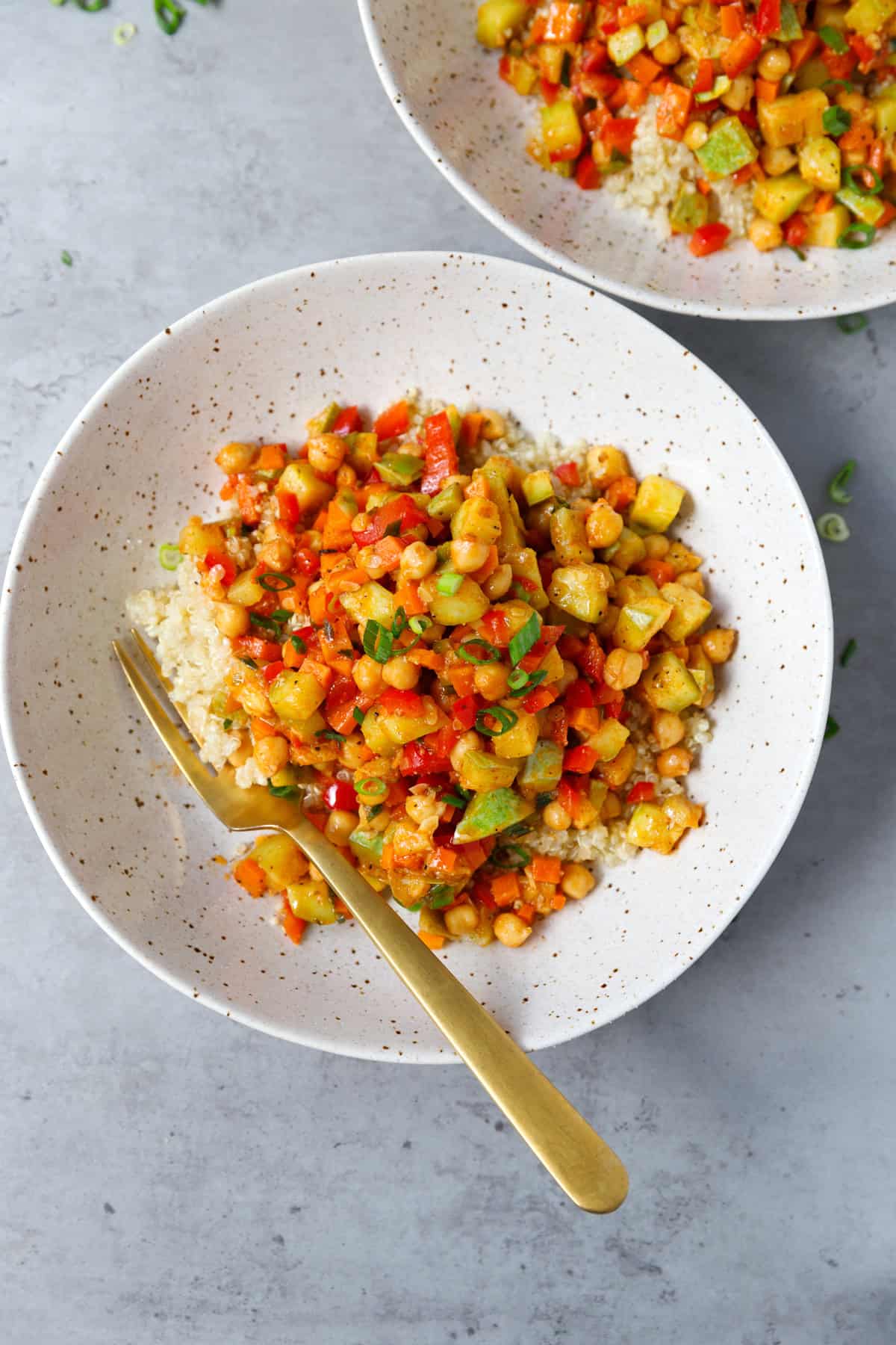 A speckled bowl with golden fork and chickpea quinoa inside