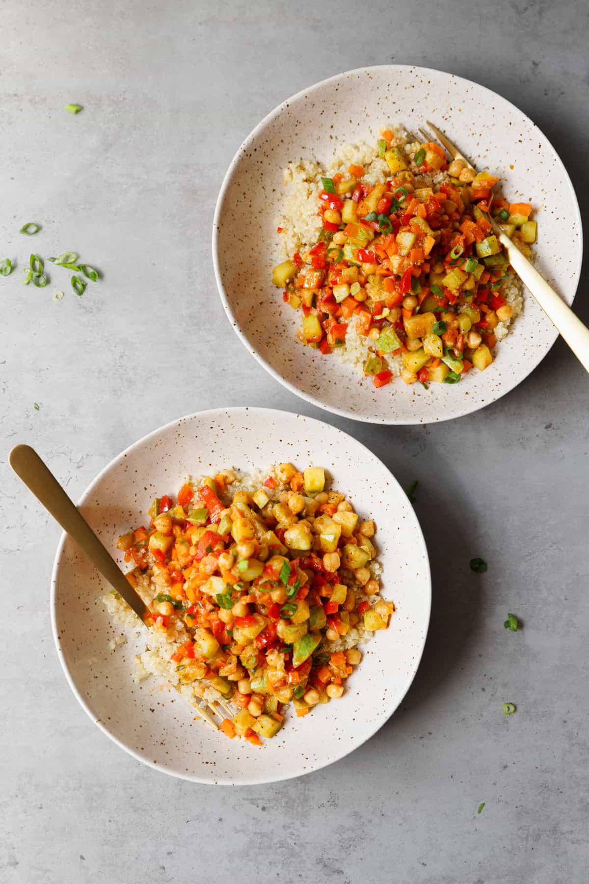 Two bowls with chickpea quinoa an golden forks at a countertop