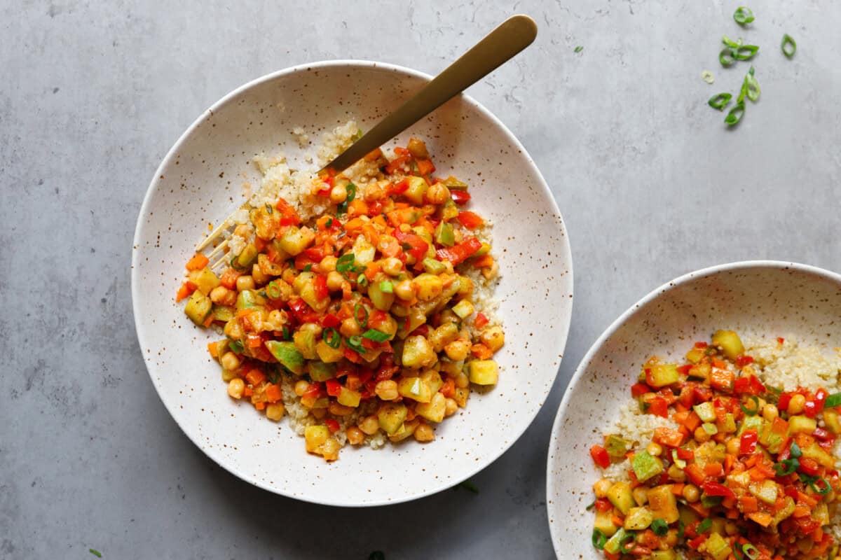 Two bowls with quinoa with vegetables and chickpeas at a countertop