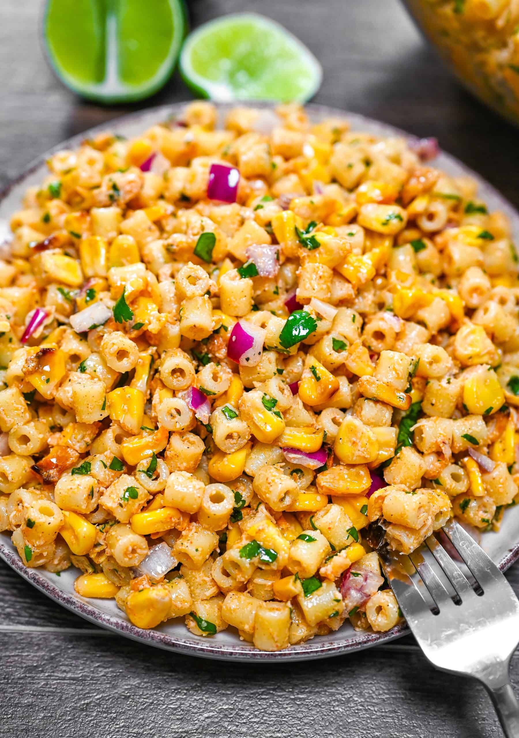A plate with creamy Elote pasta salad, topped with parsley