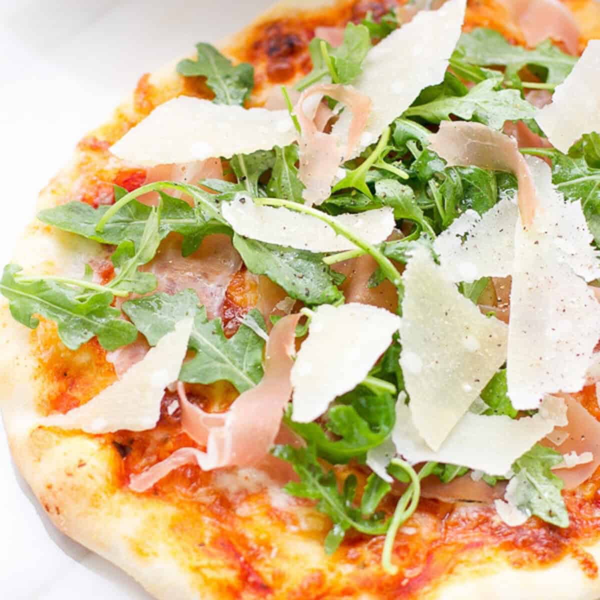 Italian Prosciutto and arugula pizza on a cutting board