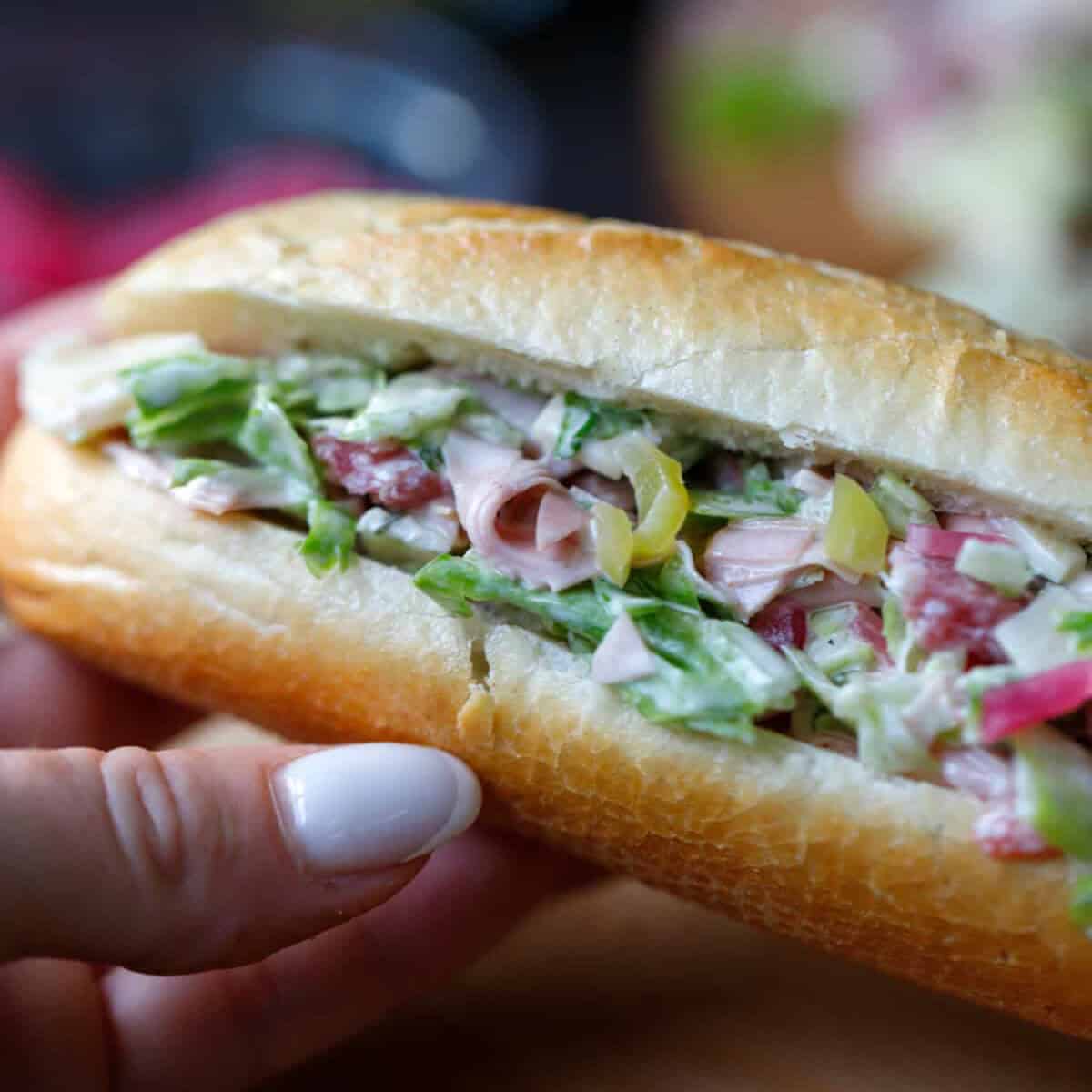A hand holding an Italian Sub Sandwich