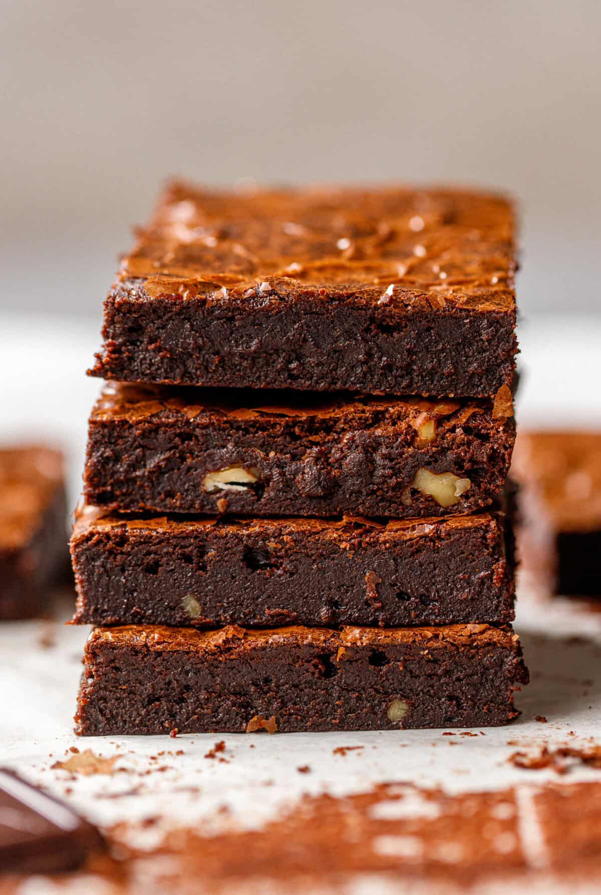 Stack of rich chocolate brownies with crisp tops and dense, fudgy centers.