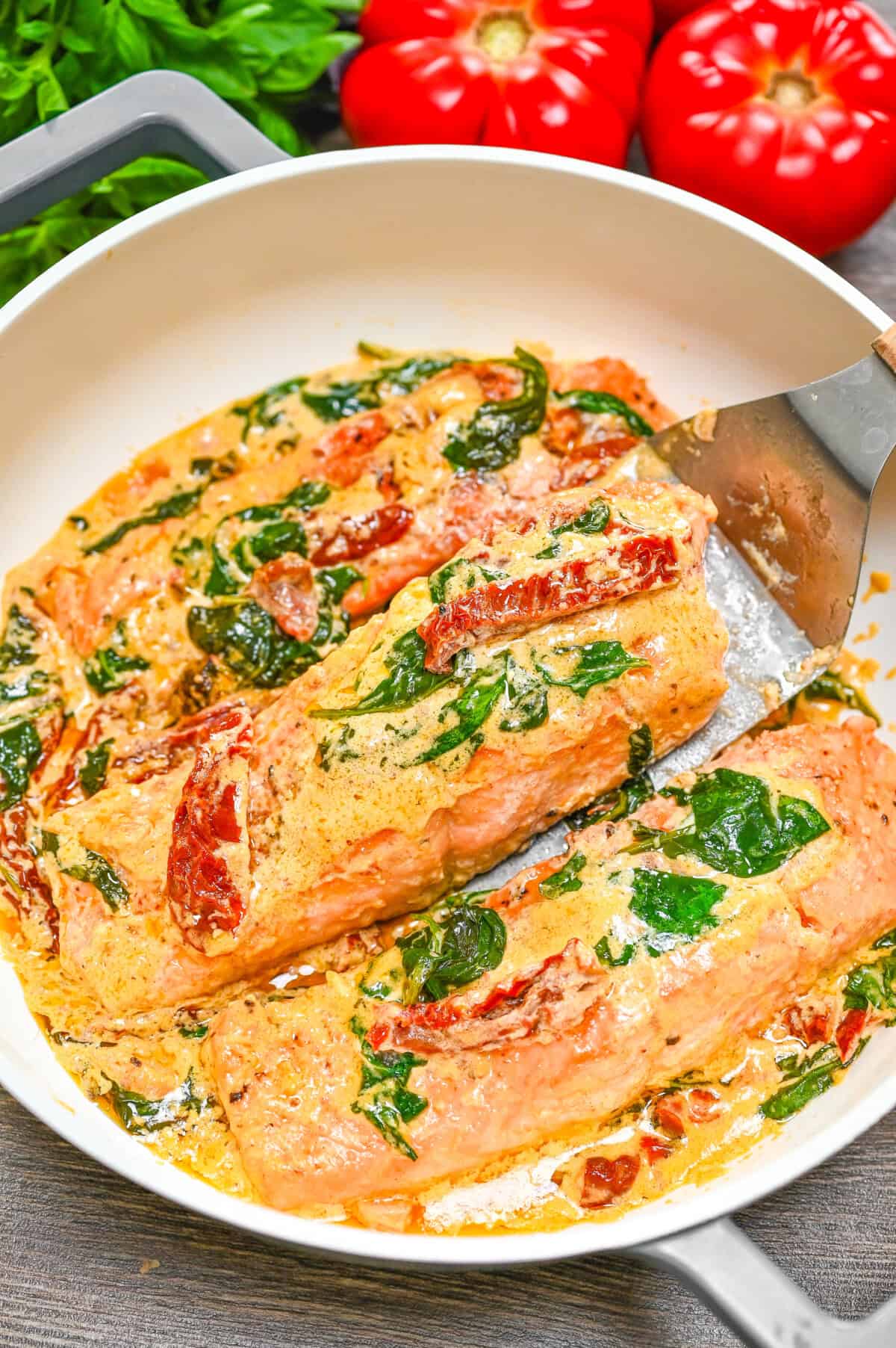 Pan-seared salmon fillets simmering in a creamy Tuscan sauce with spinach and sun-dried tomatoes.

